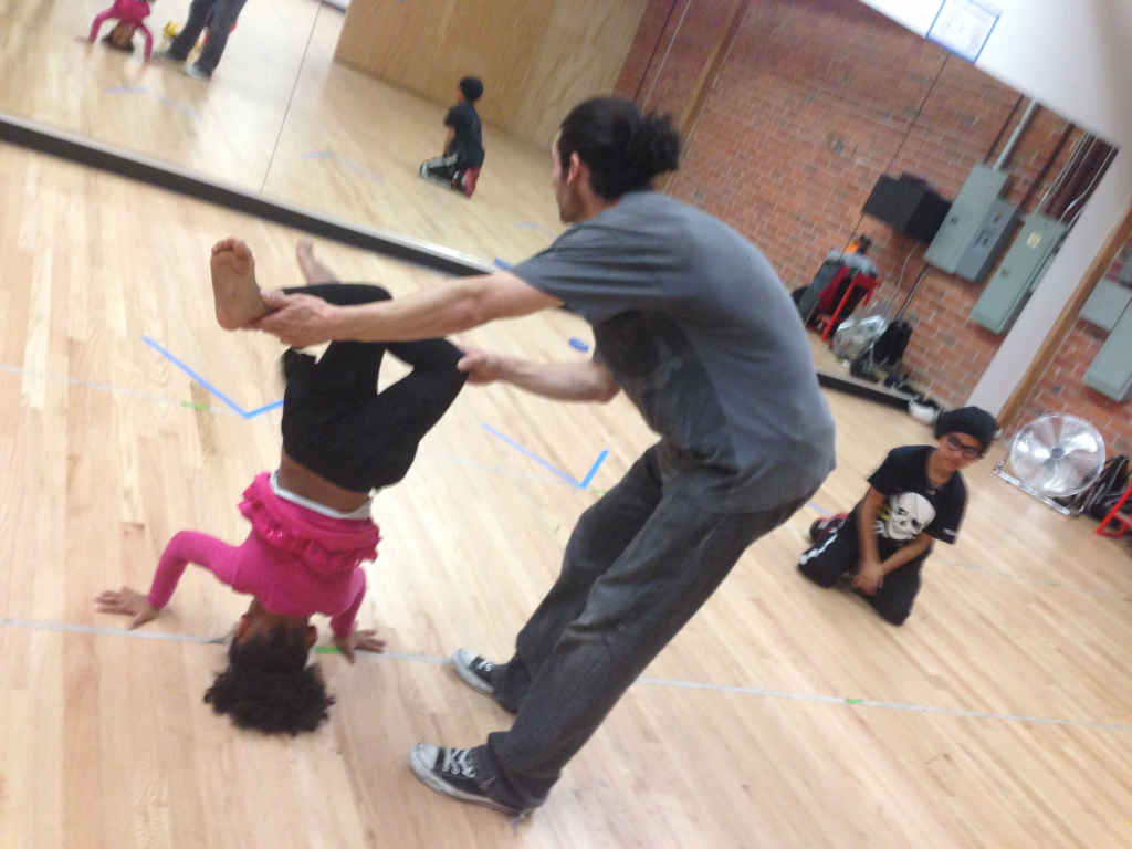 Drew Looner supports a student practicing a headstand during a breaking class at Destiny Arts in Oakland.